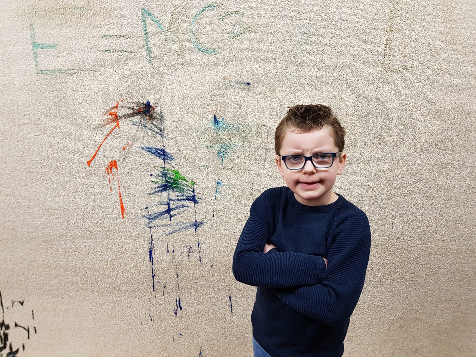 Little artist standing by paint scribbles on a bleach cleanable carpet