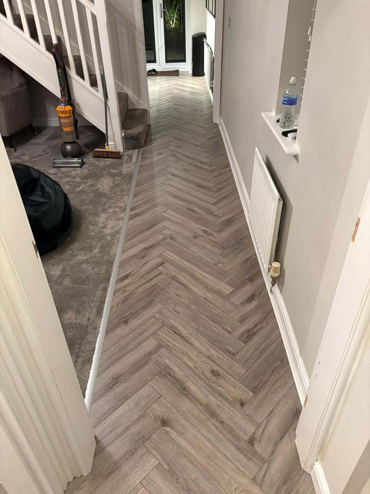 Grey herringbone LVT hallway with neat transition to stair carpet