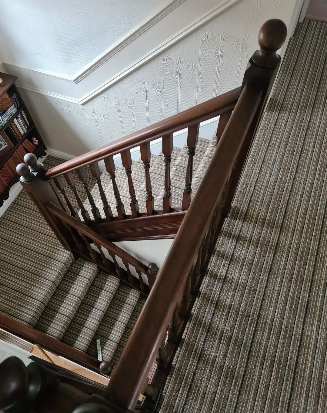 Striped stair carpet around a dark wooden banister