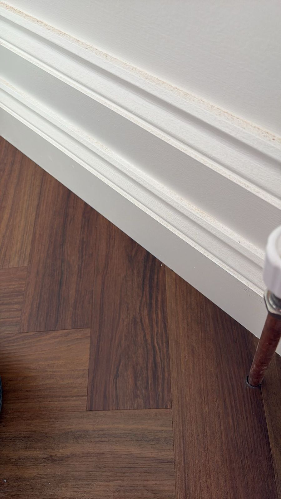 Walnut herringbone LVT with neat finish against white skirting